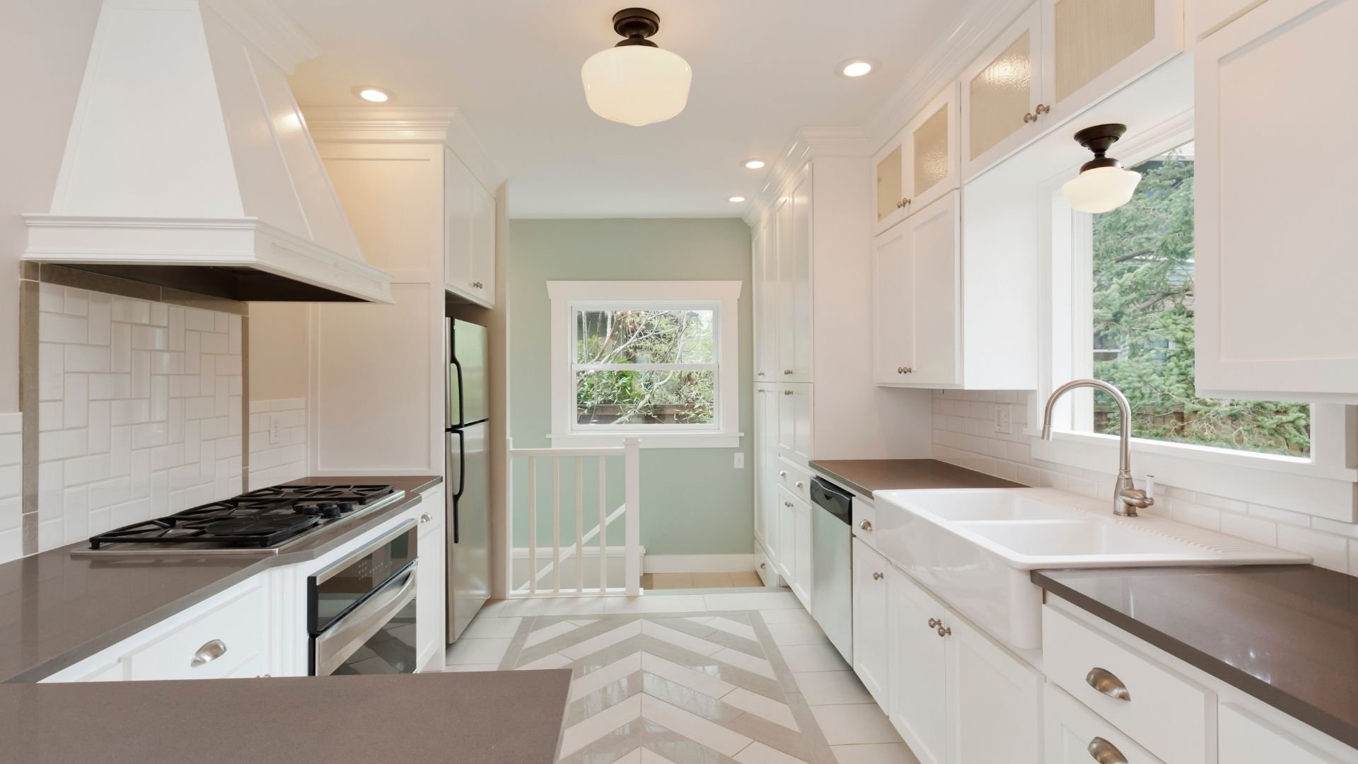 Modern bright kitchen with white cabinets, stainless steel appliances, and natural light from windows.
