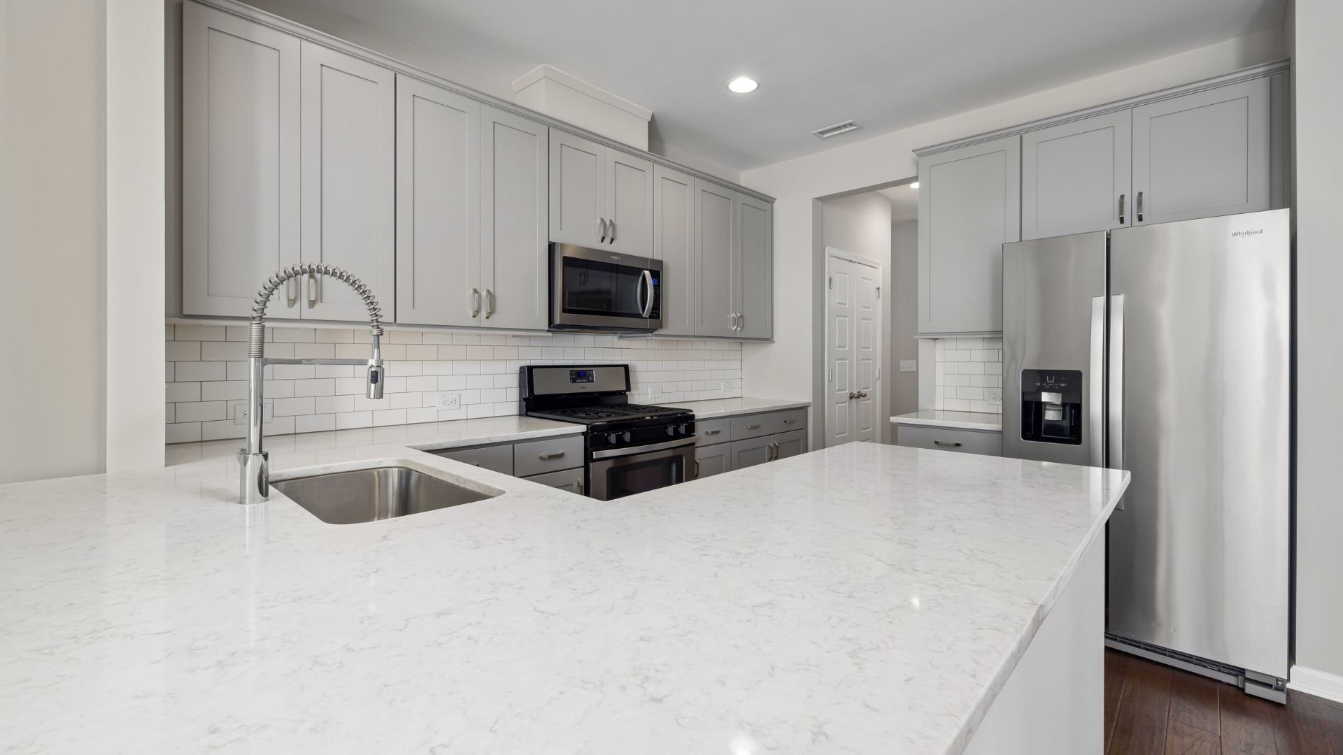 Modern kitchen with white cabinets, marble countertops, stainless steel appliances, and subway tile backsplash.