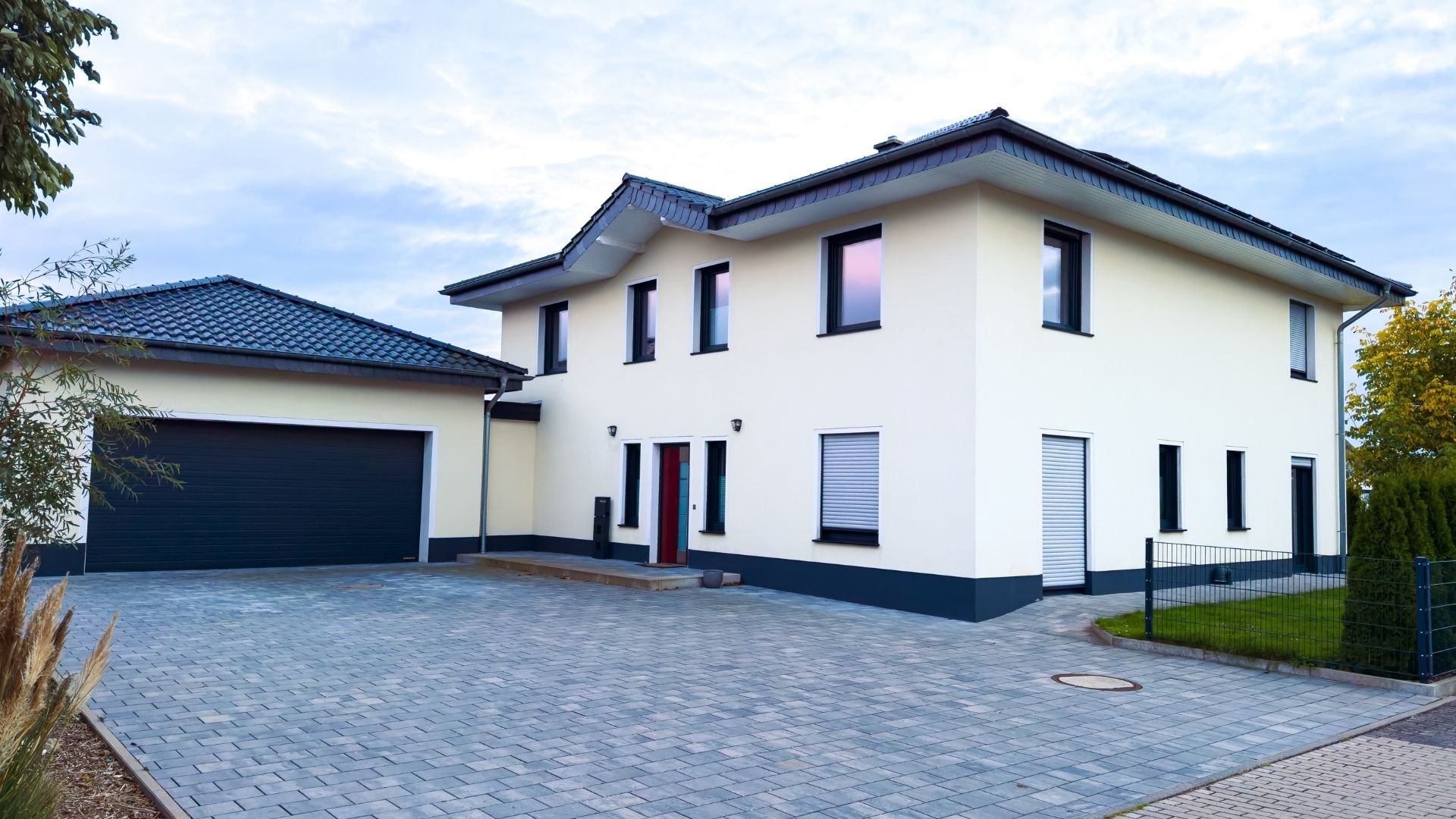 Modern two-story white house with dark roof, garage, and paved driveway